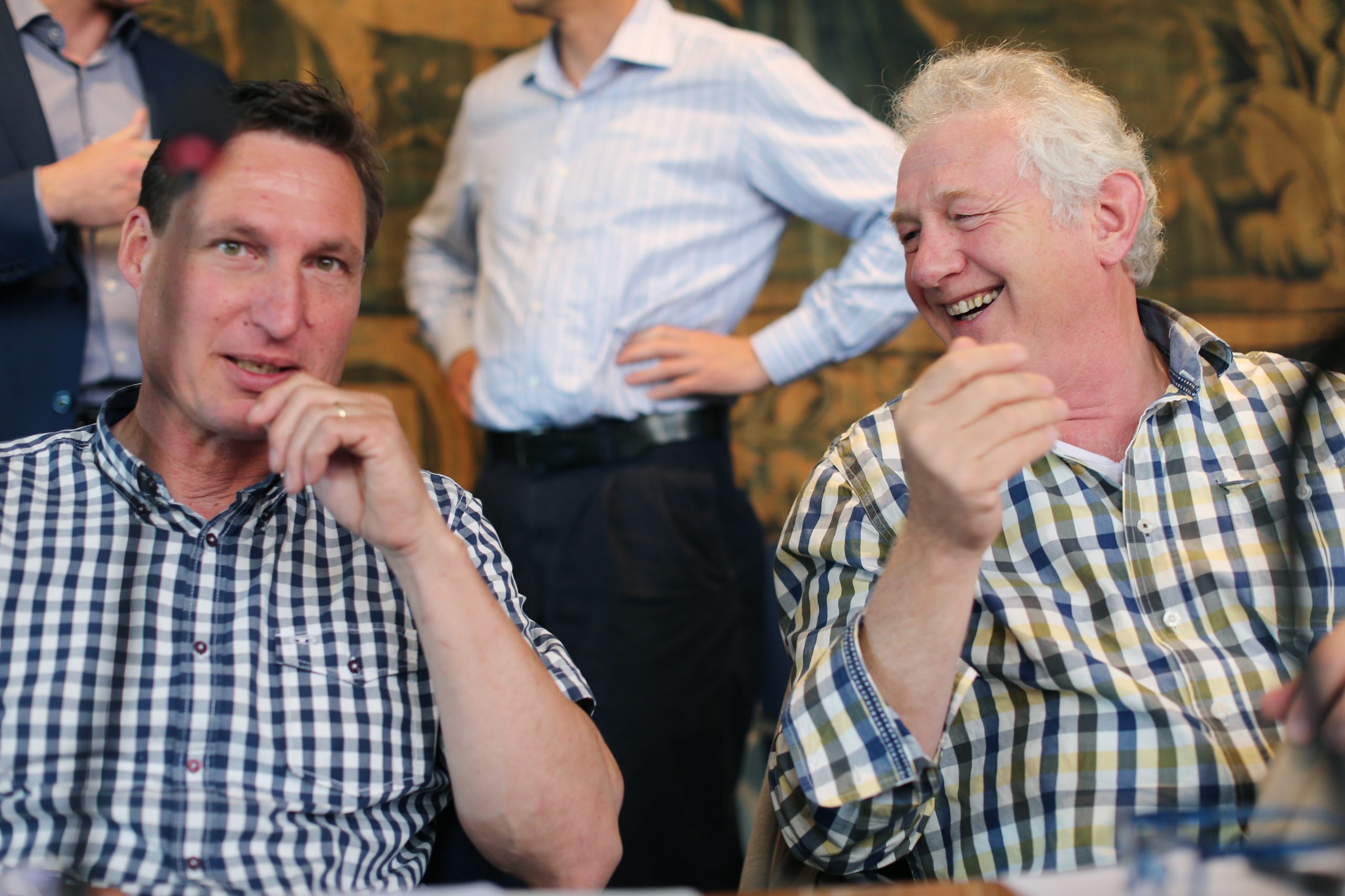 Verbroederen tijdens de Schelderaad: twee raadsleden lachen samen om een grap.