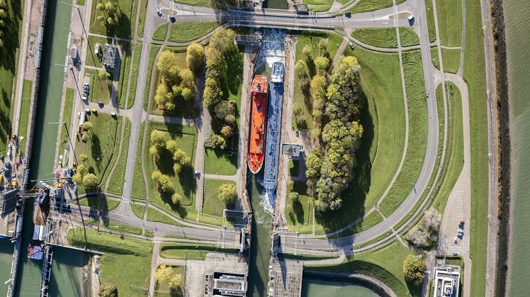 Luchtfoto van een kanaal en een haventje waar 2 schepen in liggen/ elkaar passeren