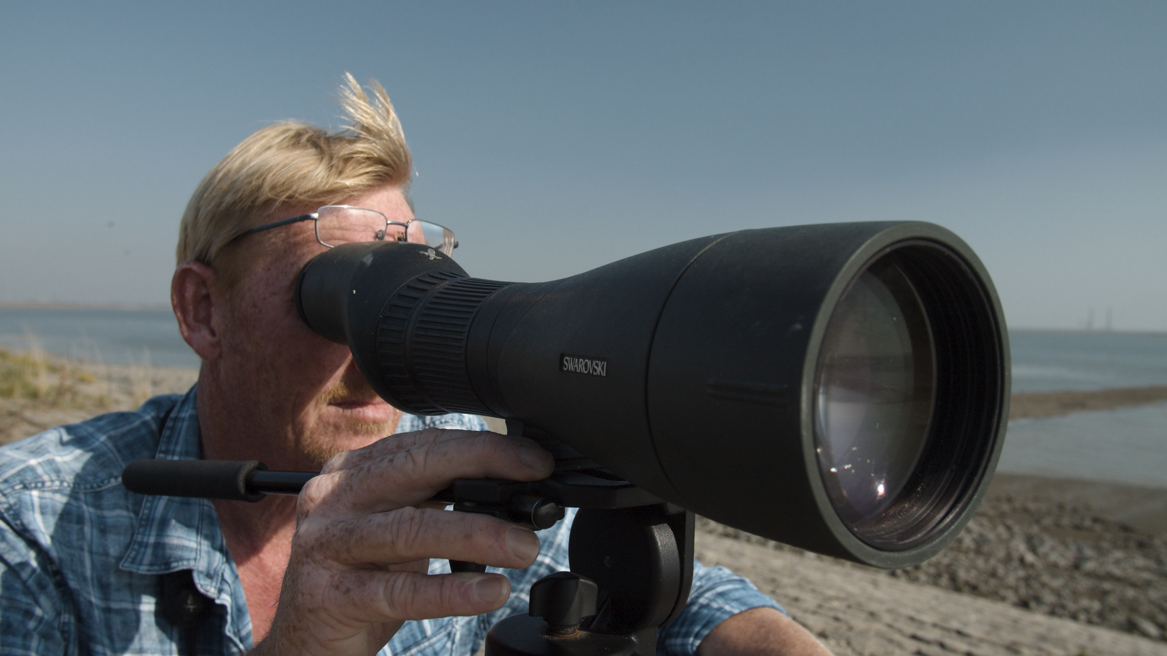 Man met grote verrekijker voert vogeltellingen uit.