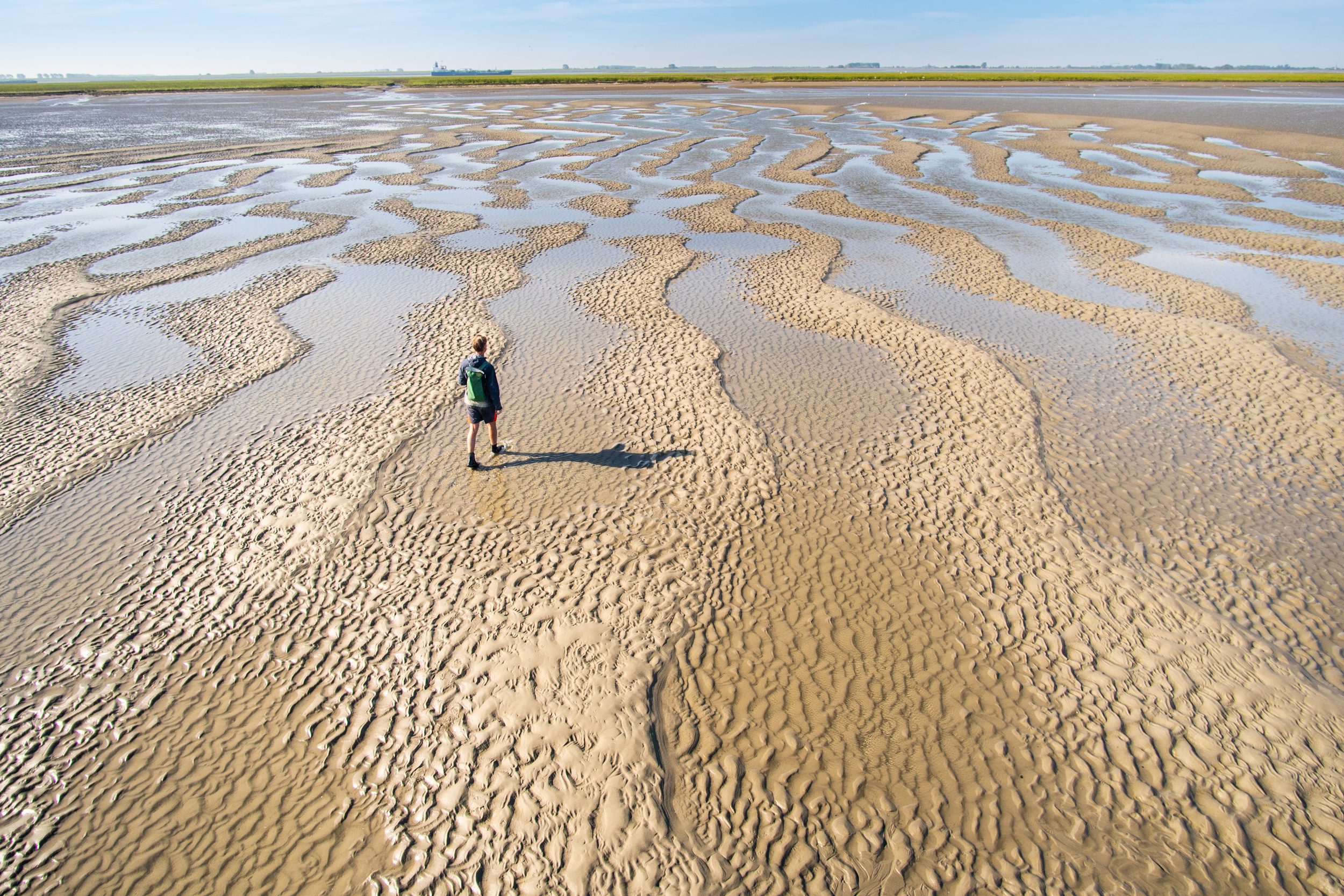 Foto van man die wandelt op drooggevallen zandplaten