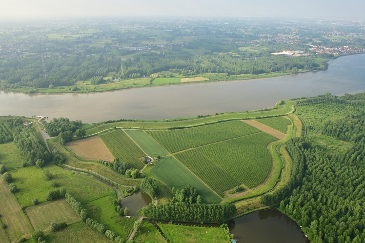 Luchtfoto van een kanaal met natuur aan beide zijden.